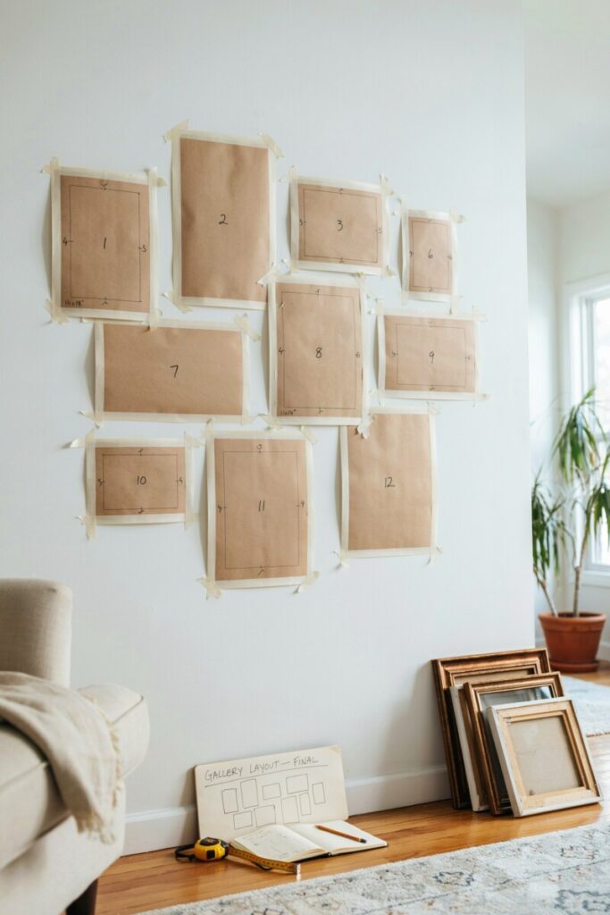 Kraft paper templates taped to a white wall showing the planned layout of a twelve-frame gallery wall before hanging