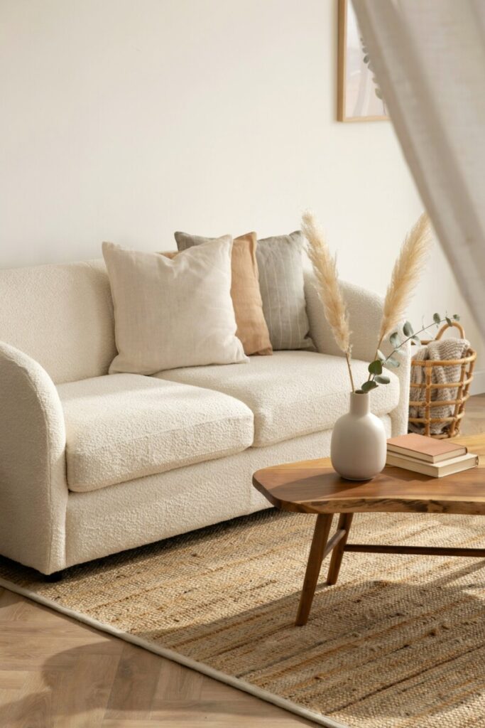 Layered natural textures in a warm minimalist living room including bouclé, linen, jute, wood, and stone